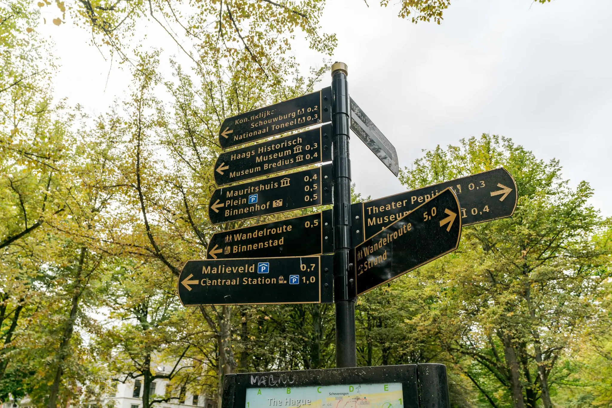 Wegwijzer op het Lange Voorhout in Den Haag met richtingaanwijzers naar bezienswaardigheden en wandelroutes.